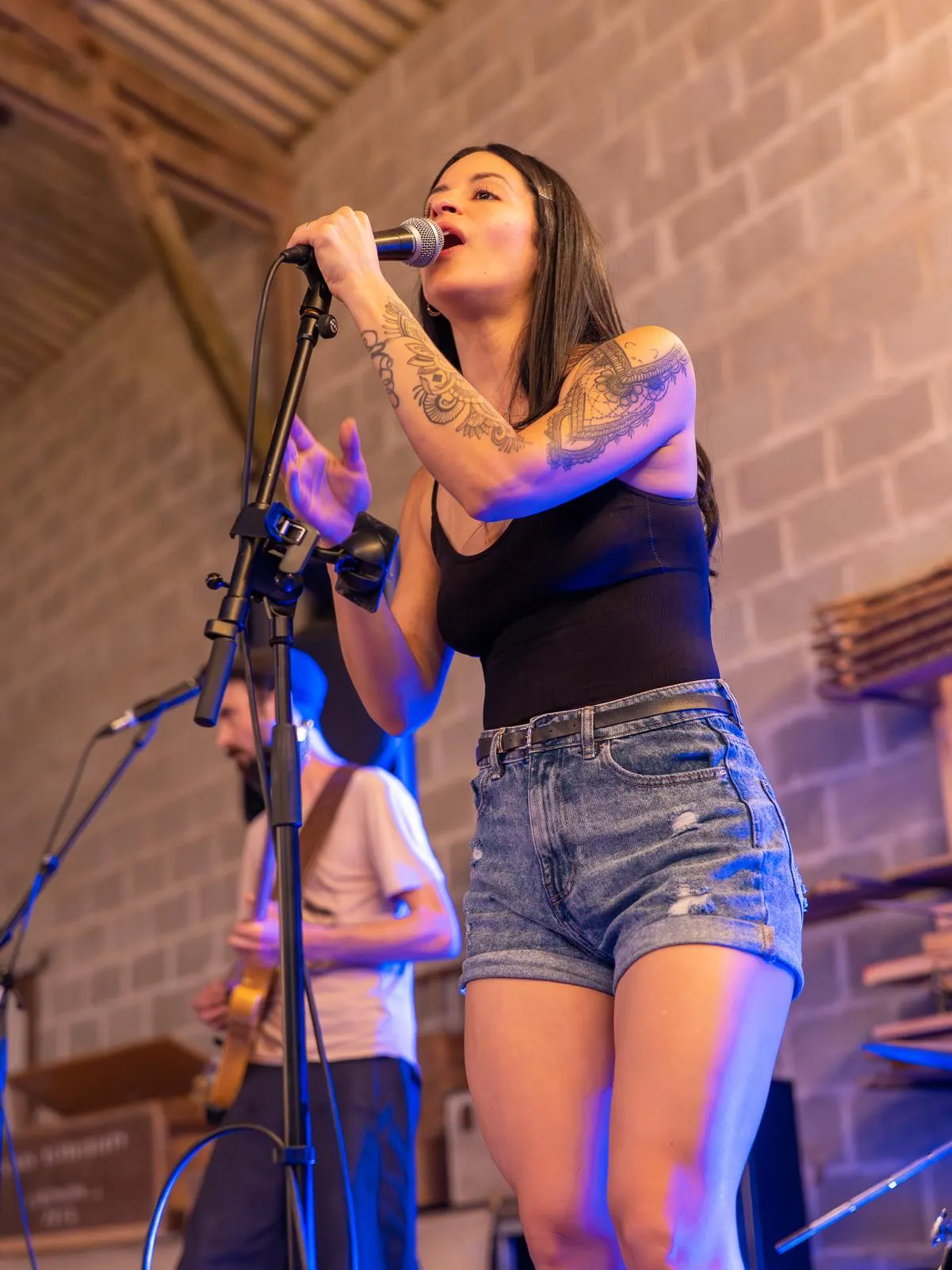Alejandra en plein concert, micro en main, accompagnée d'un trompettiste